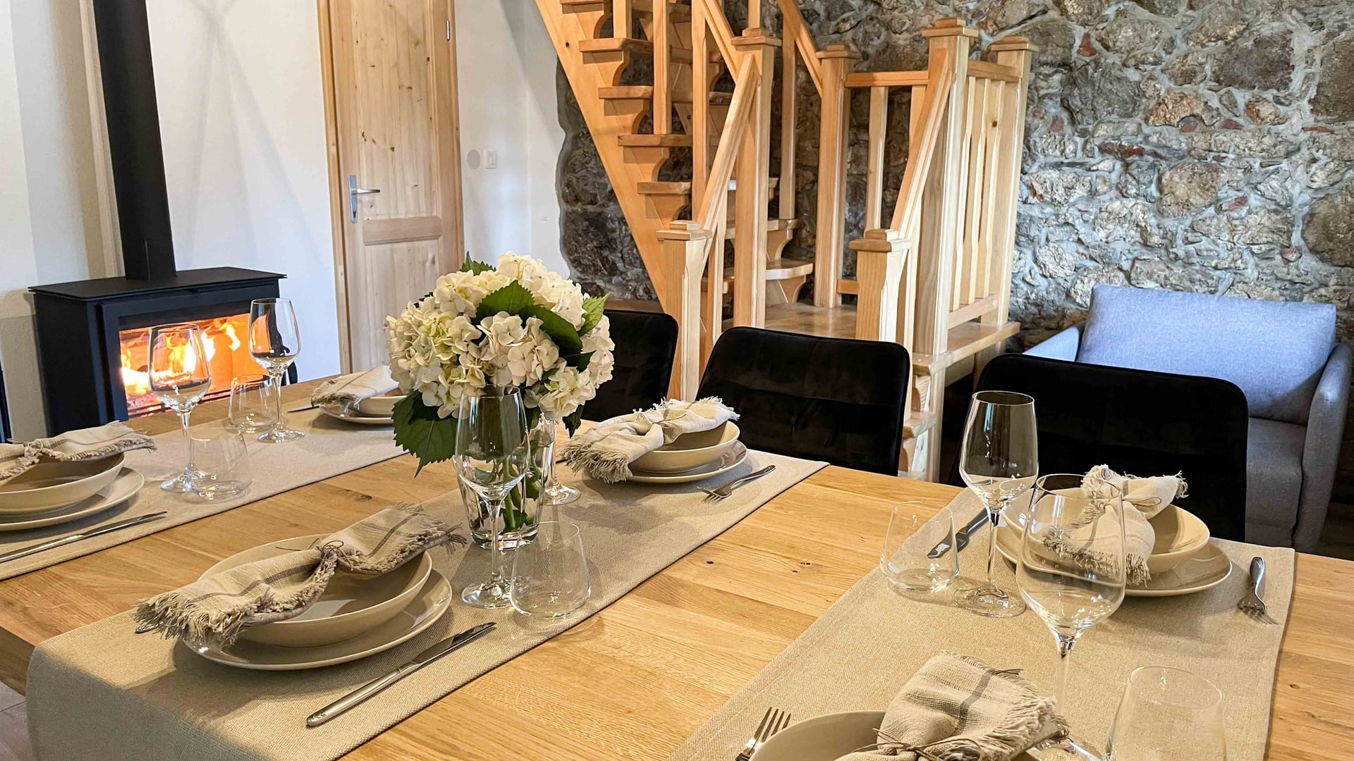 Kuća Amalia – stol za blagovanje s kamenim zidom i peći na drva