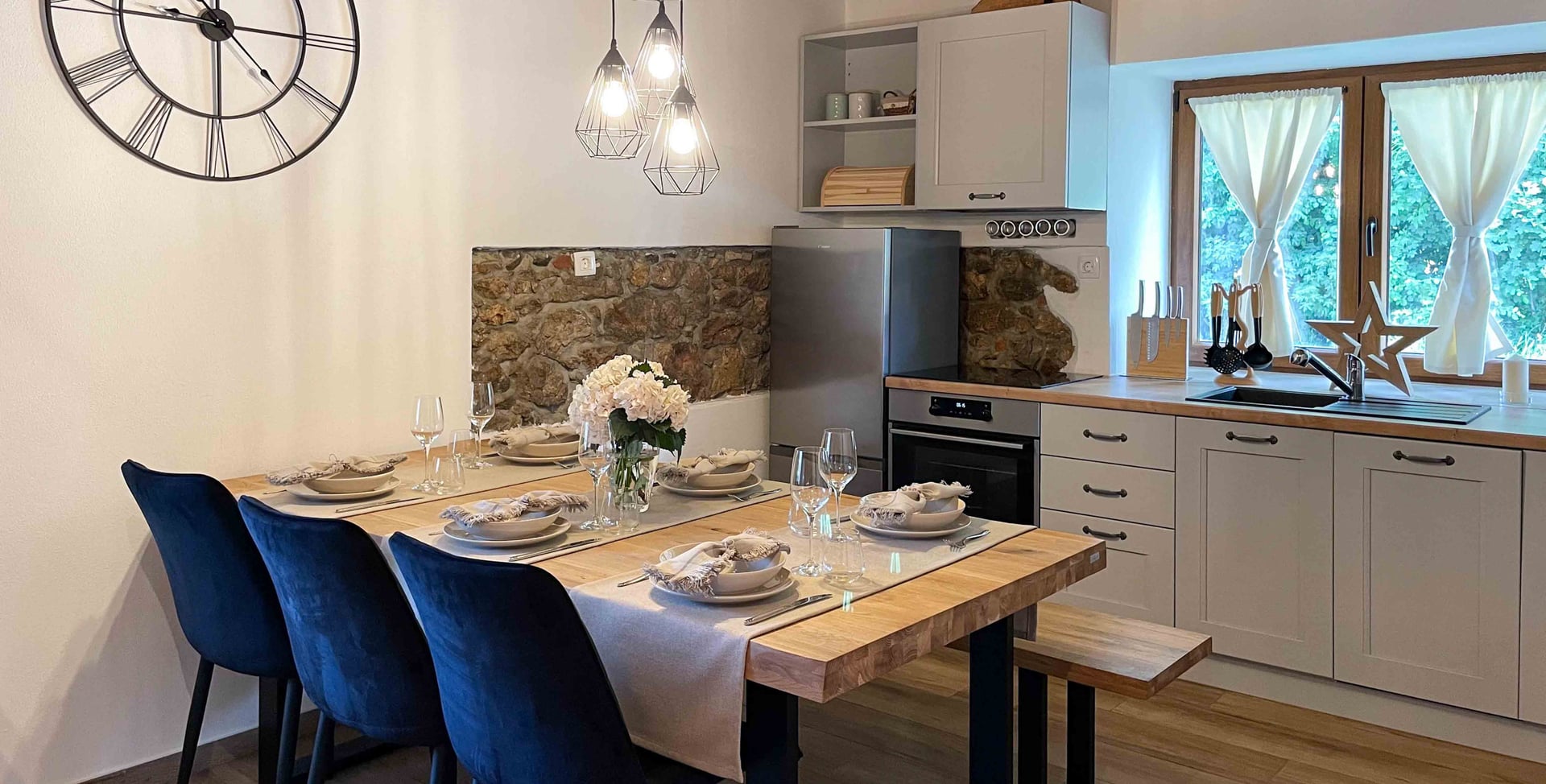 Kuća Amalia – kuhinja i blagovaonica s plavim stolicama i satom