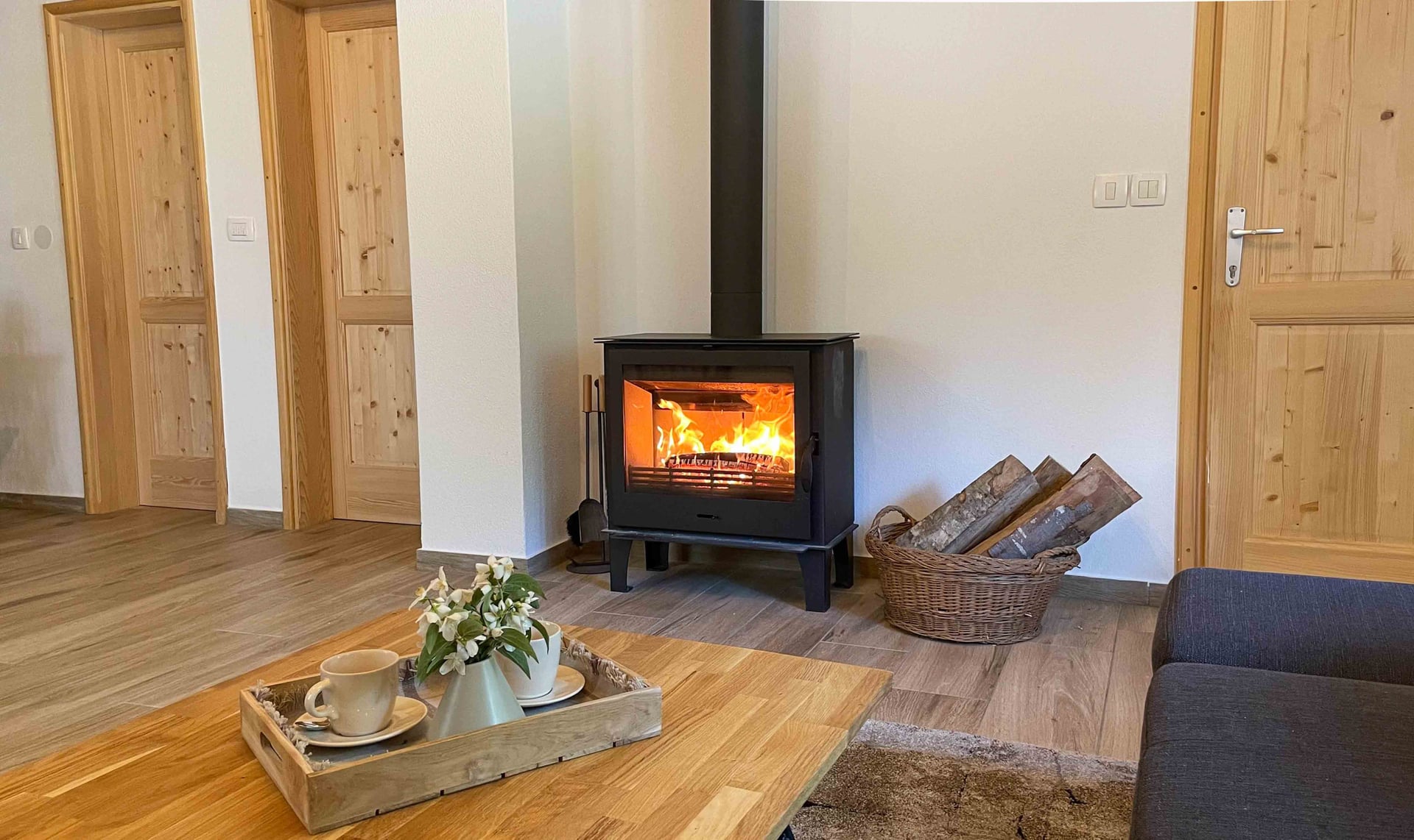 Kuća Amalia – peć na drva s košarom za drva u dnevnom boravku